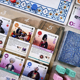 Pax Pamir: Second Edition – nærbillede af kort fra kortrækken med illustrationer af historiske personer og en markedsscene